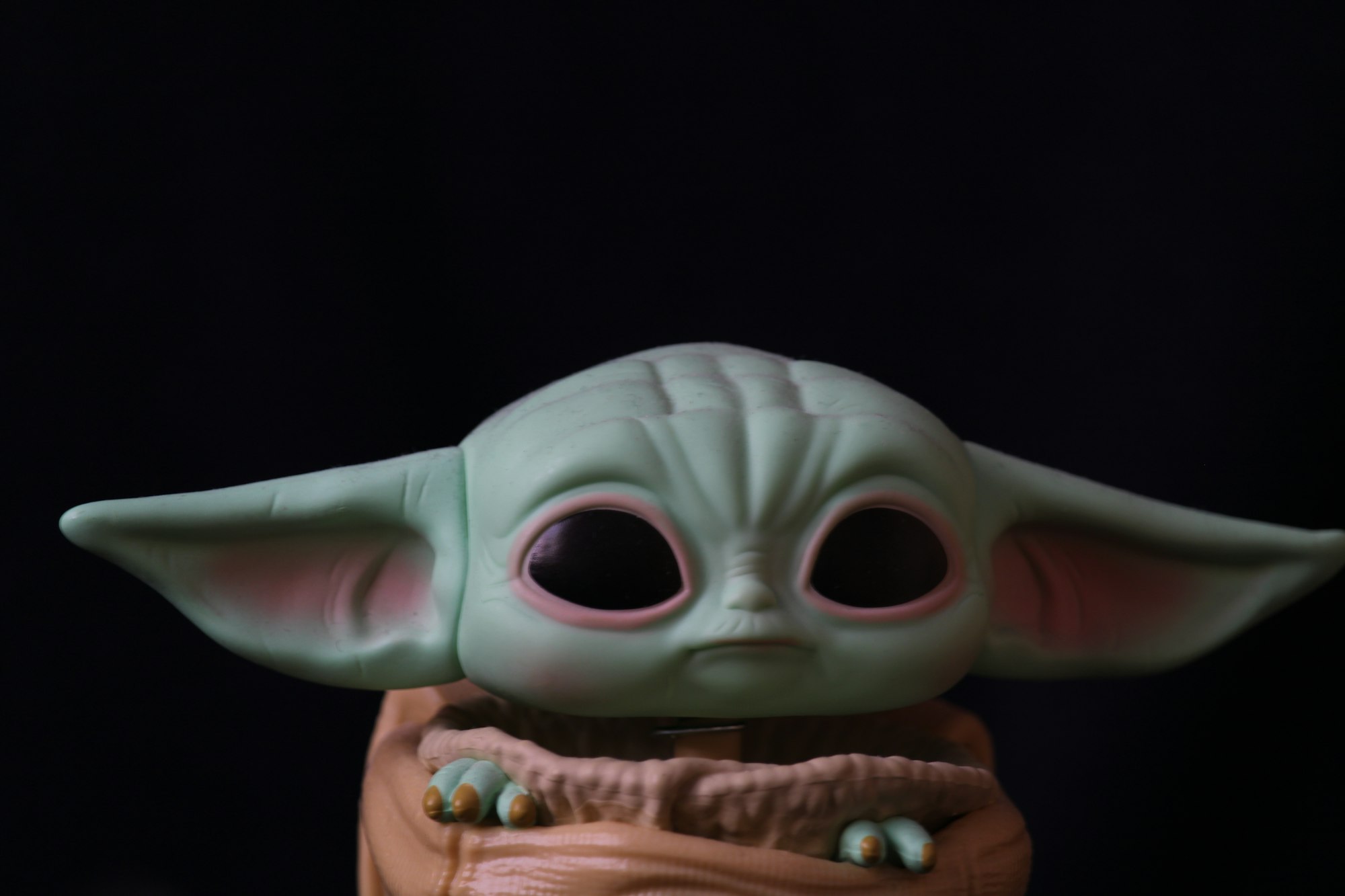 Figure of a popular green alien character with large ears and eyes, against a dark background.