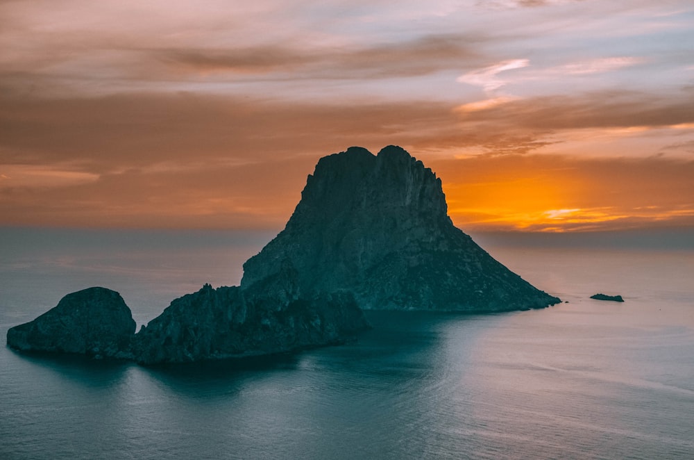 Una puesta de sol sobre un cuerpo de agua con una montaña al fondo