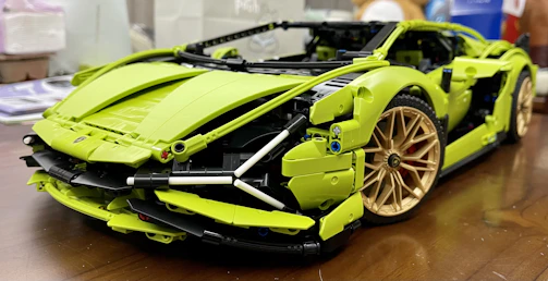 A colorful metal model car built from classic construction set pieces on a wooden table.