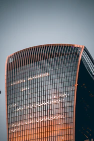 Glass skyscraper exterior in Mumbai with a subtle orange tint reflecting the city skyline.