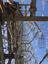 A large, complex metal structure with intricate latticed frameworks extending vertically into the sky. Several large metal beams and supports are interconnected, creating an industrial appearance.