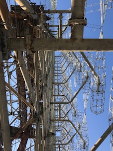 A large, complex metal structure with intricate latticed frameworks extending vertically into the sky. Several large metal beams and supports are interconnected, creating an industrial appearance.