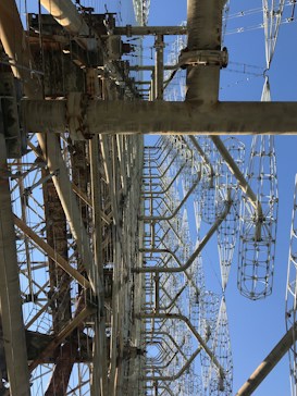 A large, complex metal structure with intricate latticed frameworks extending vertically into the sky. Several large metal beams and supports are interconnected, creating an industrial appearance.