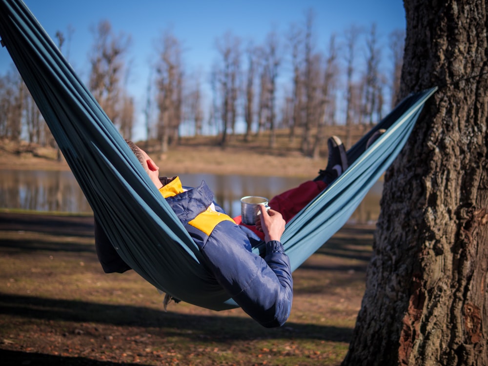 a person lying on a hammock by a tree