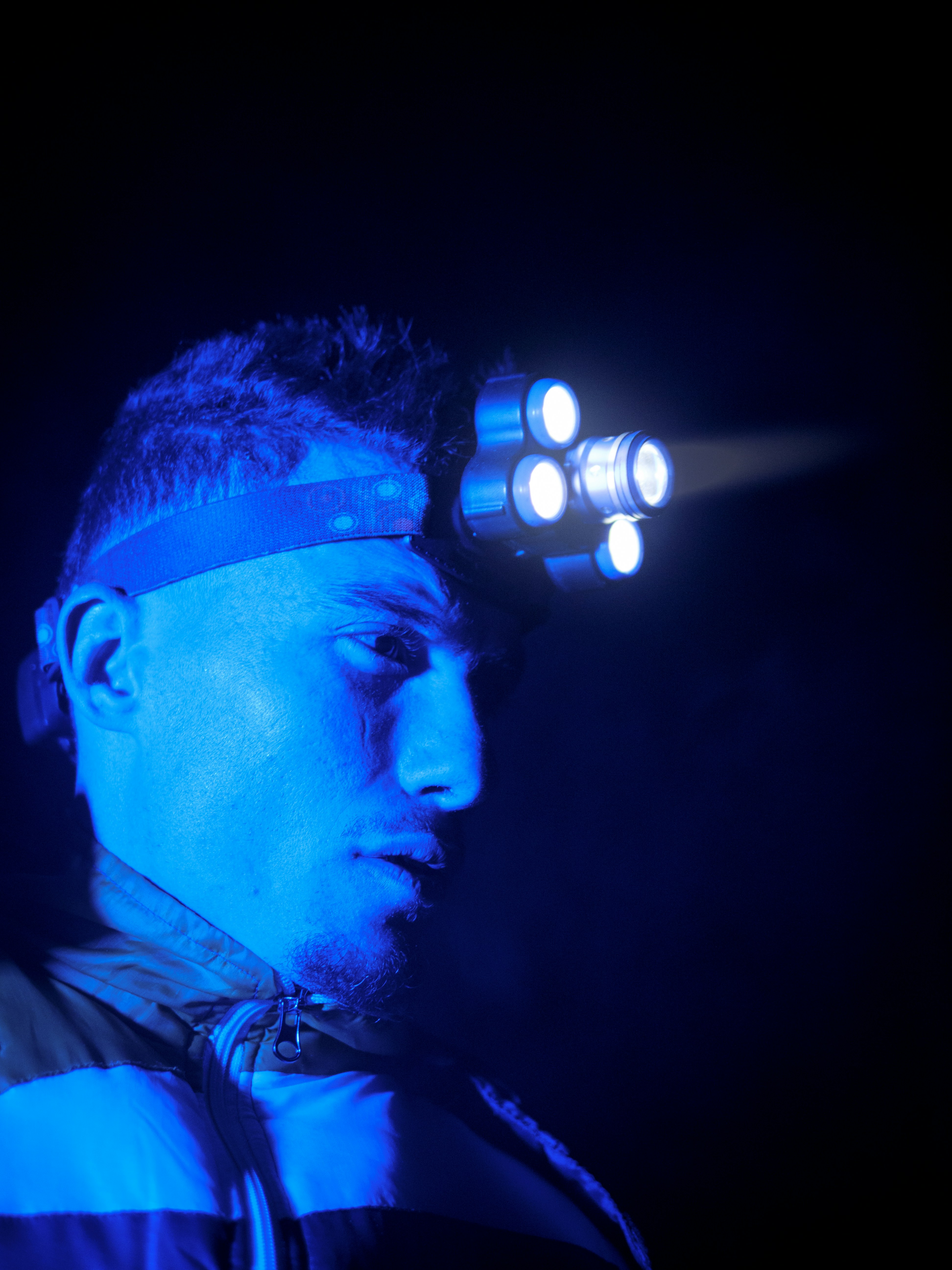 a man with a beard and blue headband in a dark room