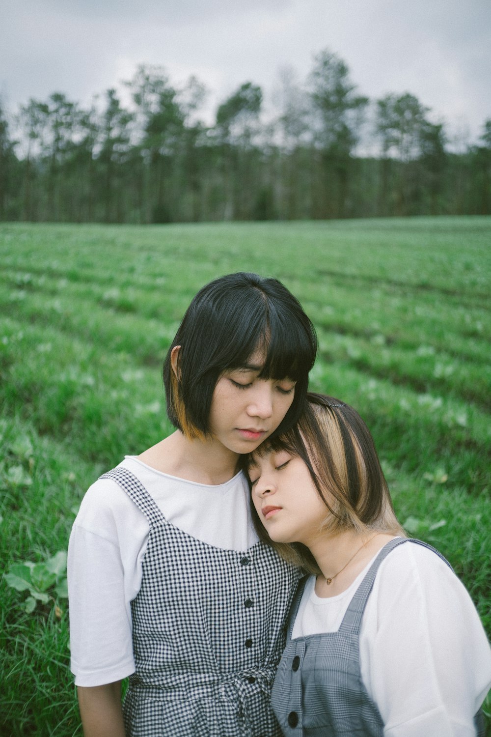 a person kissing another woman on the cheek in a field