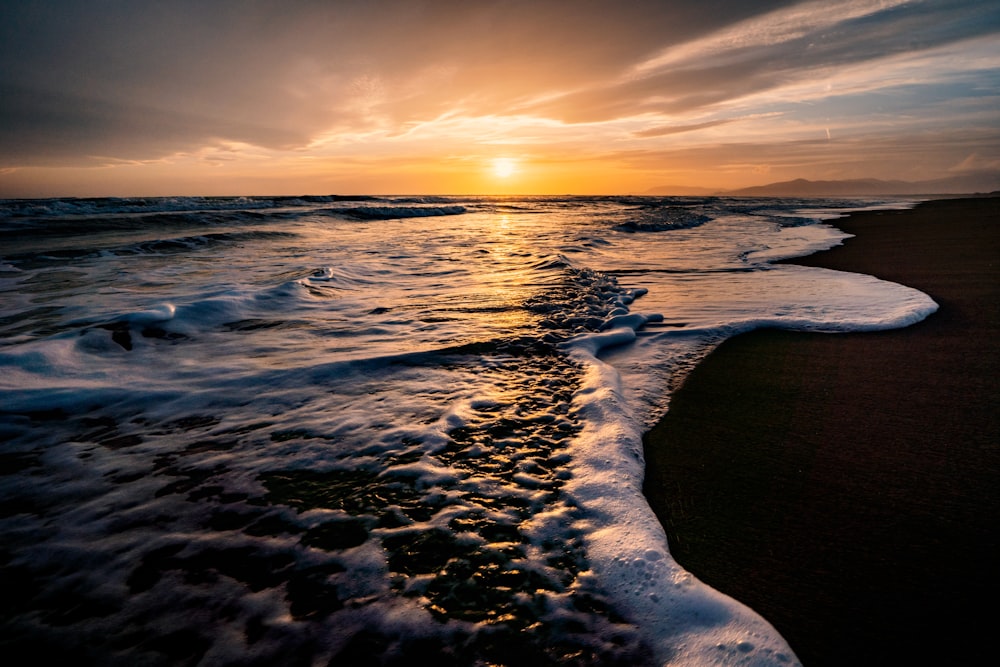 a beach with waves and a sunset