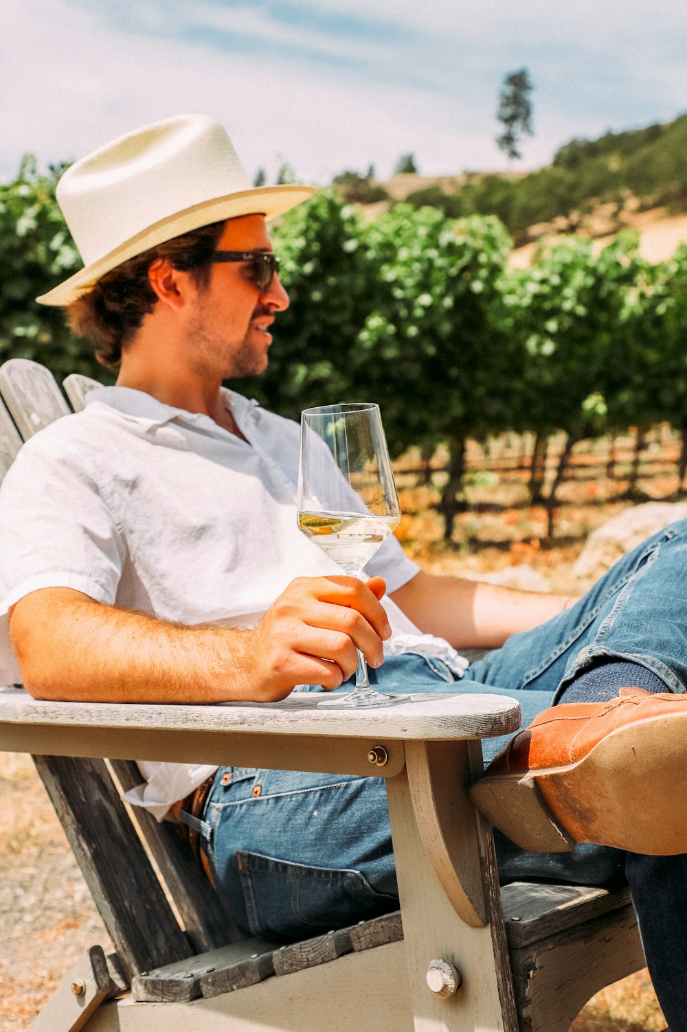 a man sitting on a bench holding a glass of beer