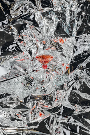 Close-up of a shimmering silver cocktail glass held by a guest against a backdrop of a lively concert crowd.