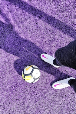a person's feet with a ball on a purple carpet