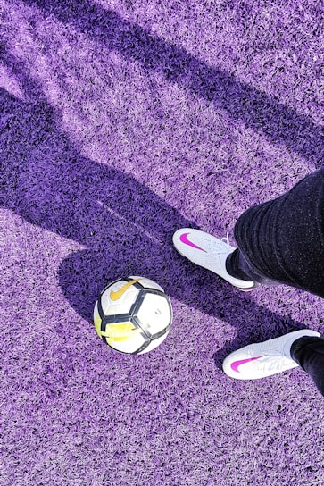 a person's feet with a ball on a purple carpet