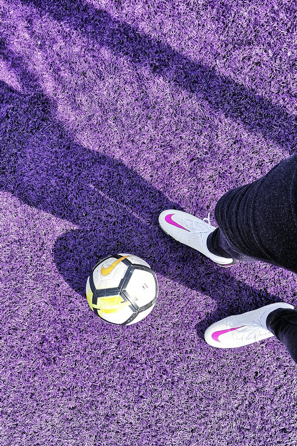 紫色のカーペットの上にボールを持つ人の足