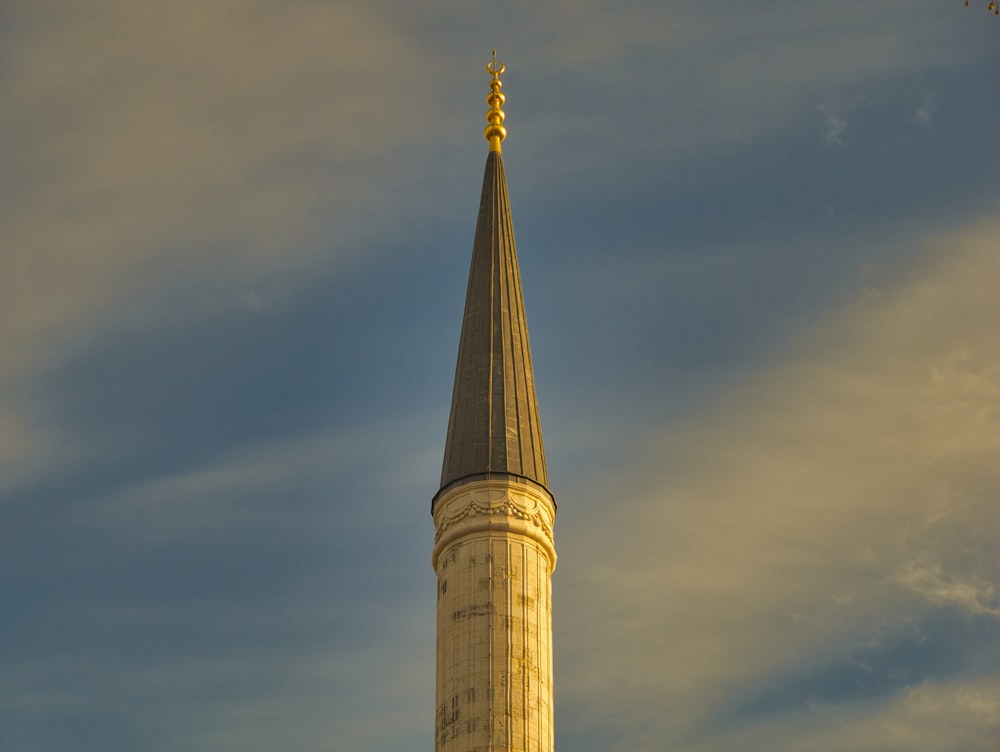 a tall pointy tower with a gold top and a gold top