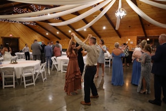 a man and woman dancing in a room with tables and chairs