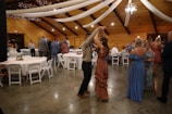 a man and woman dancing in a room with tables and chairs