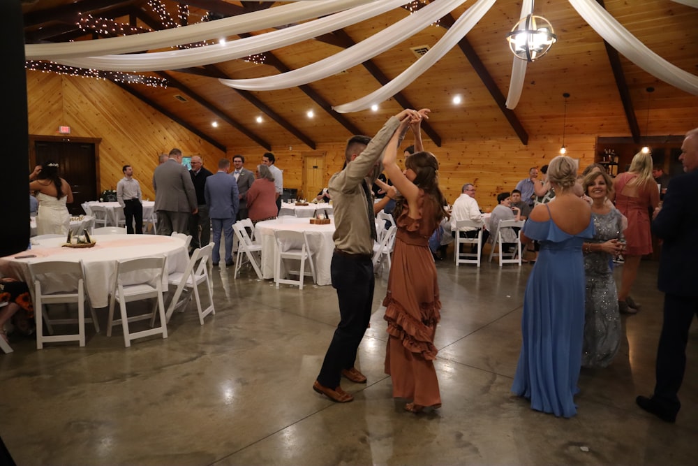 a man and woman dancing in a room with tables and chairs