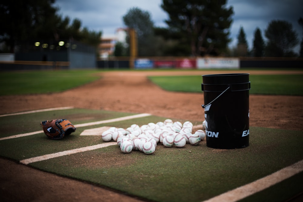 a black garbage can next to a pile of balls on a football field