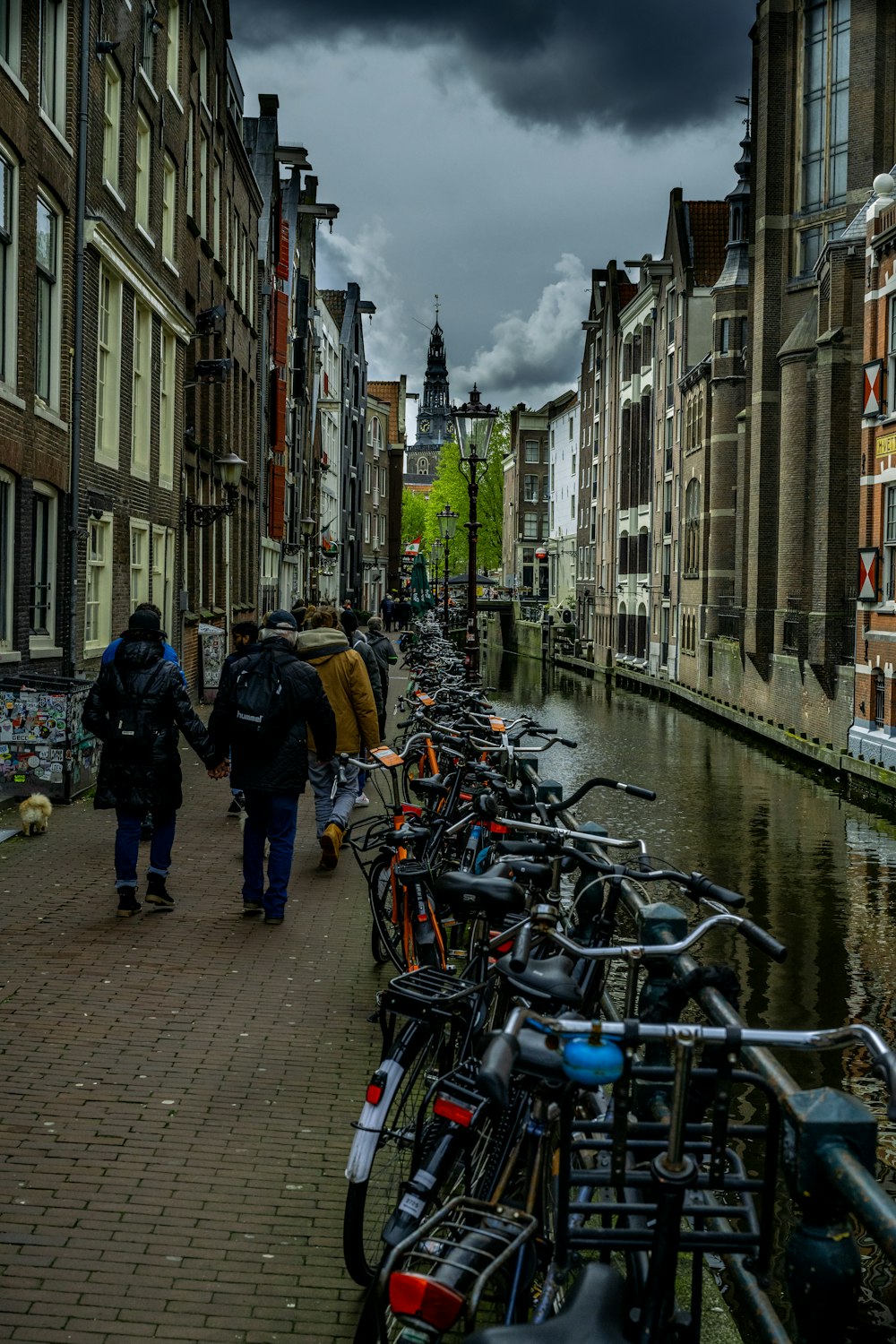 a group of people walking along a sidewalk next to a canal