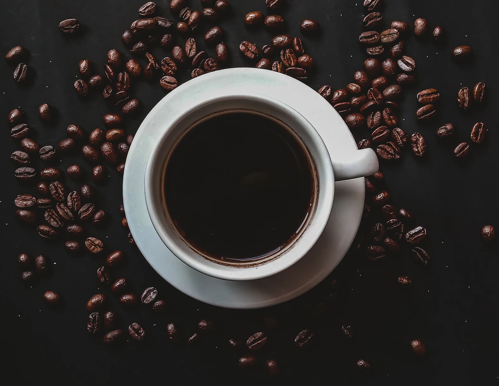 Xícara de café preto em grãos escuros com luz dramática, simbolizando o tema cafeína e nutrição esportiva