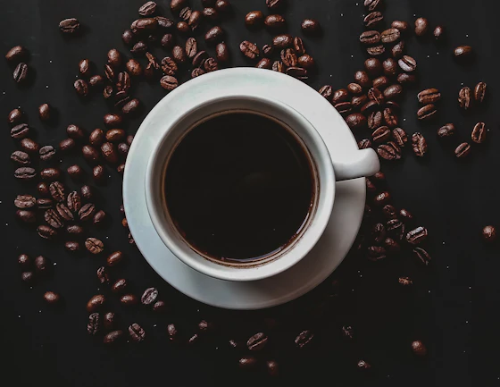 Xícara de café preto em grãos escuros com luz dramática, simbolizando o tema cafeína e nutrição esportiva
