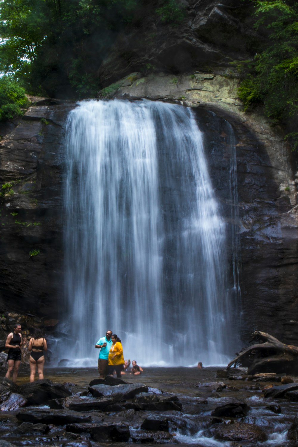 a group of people standing next to a waterfall