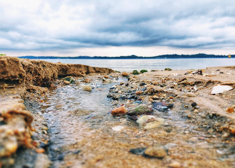 a rocky beach with a body of water in the background