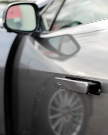 Close-up of a technician carefully installing a sleek accessory on a car door handle.