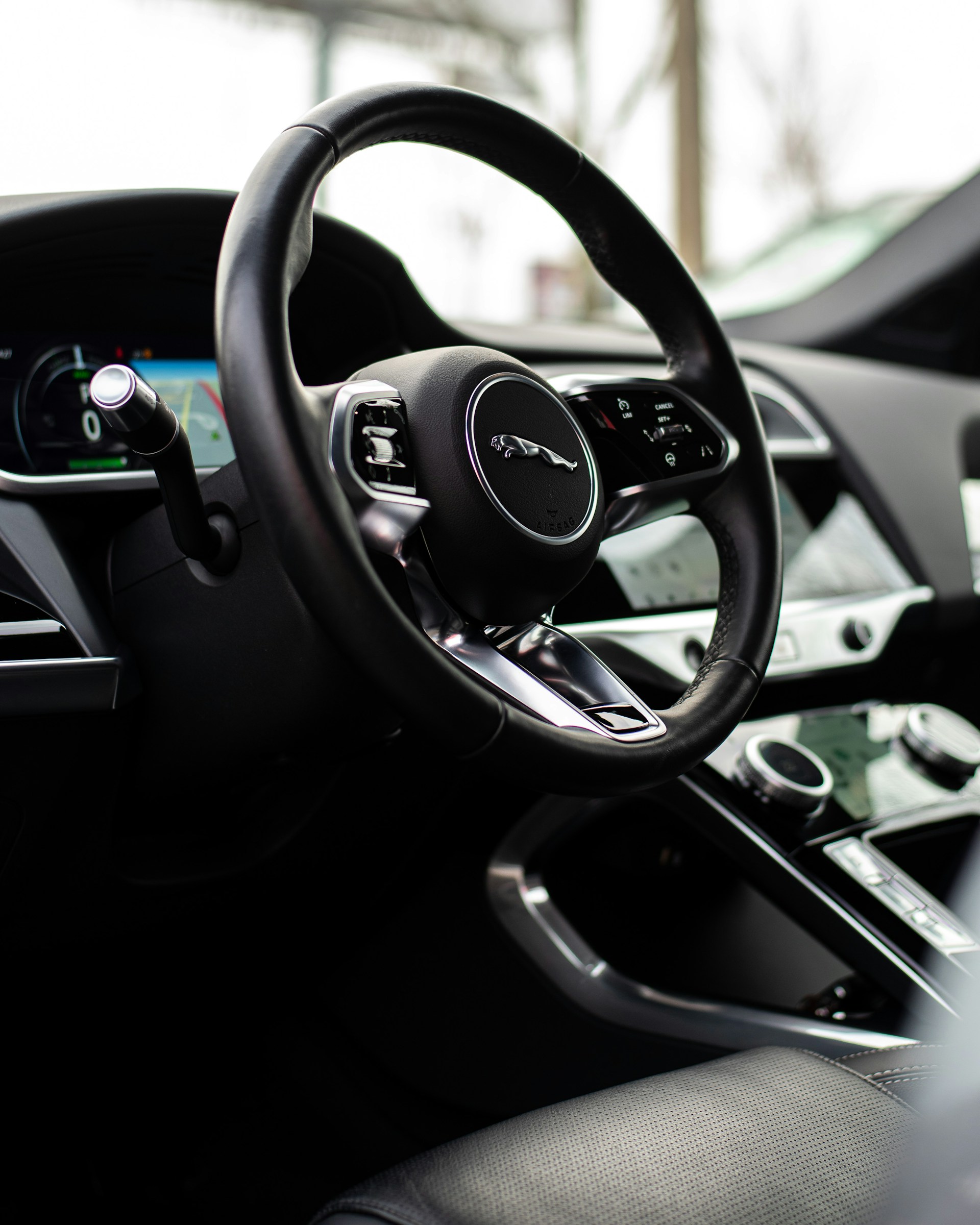 A close-up of a luxury car's dashboard featuring modern controls and a leather-wrapped steering wheel.