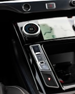 A close-up view of a car's center console featuring a digital temperature control knob set at 22 degrees, gear shift buttons labeled D, N, R, and P, and part of a touchscreen interface displaying seat and climate settings.