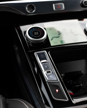 A close-up view of a car's center console featuring a digital temperature control knob set at 22 degrees, gear shift buttons labeled D, N, R, and P, and part of a touchscreen interface displaying seat and climate settings.