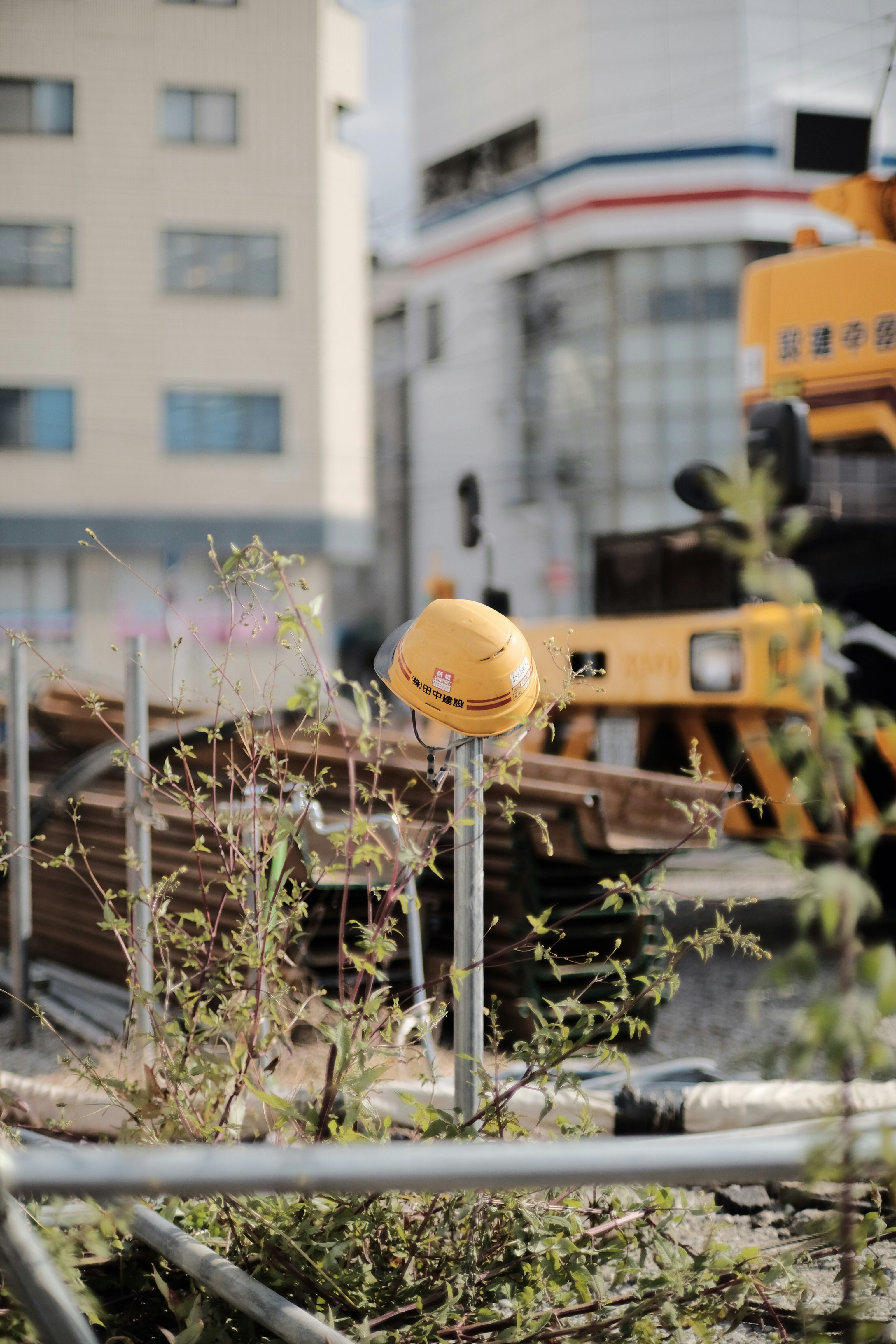 Yellow construction hard hat on dark industrial surface, overhead lighting, sharp shadows