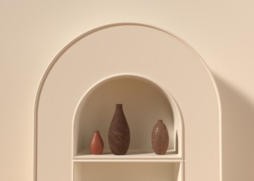 A set of minimalist ceramic vases in soft pastel colors arranged on a shelf.
