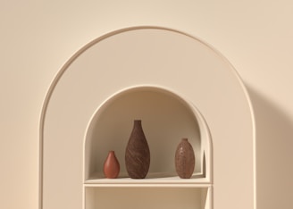 A set of minimalist ceramic vases in soft pastel colors arranged on a shelf.