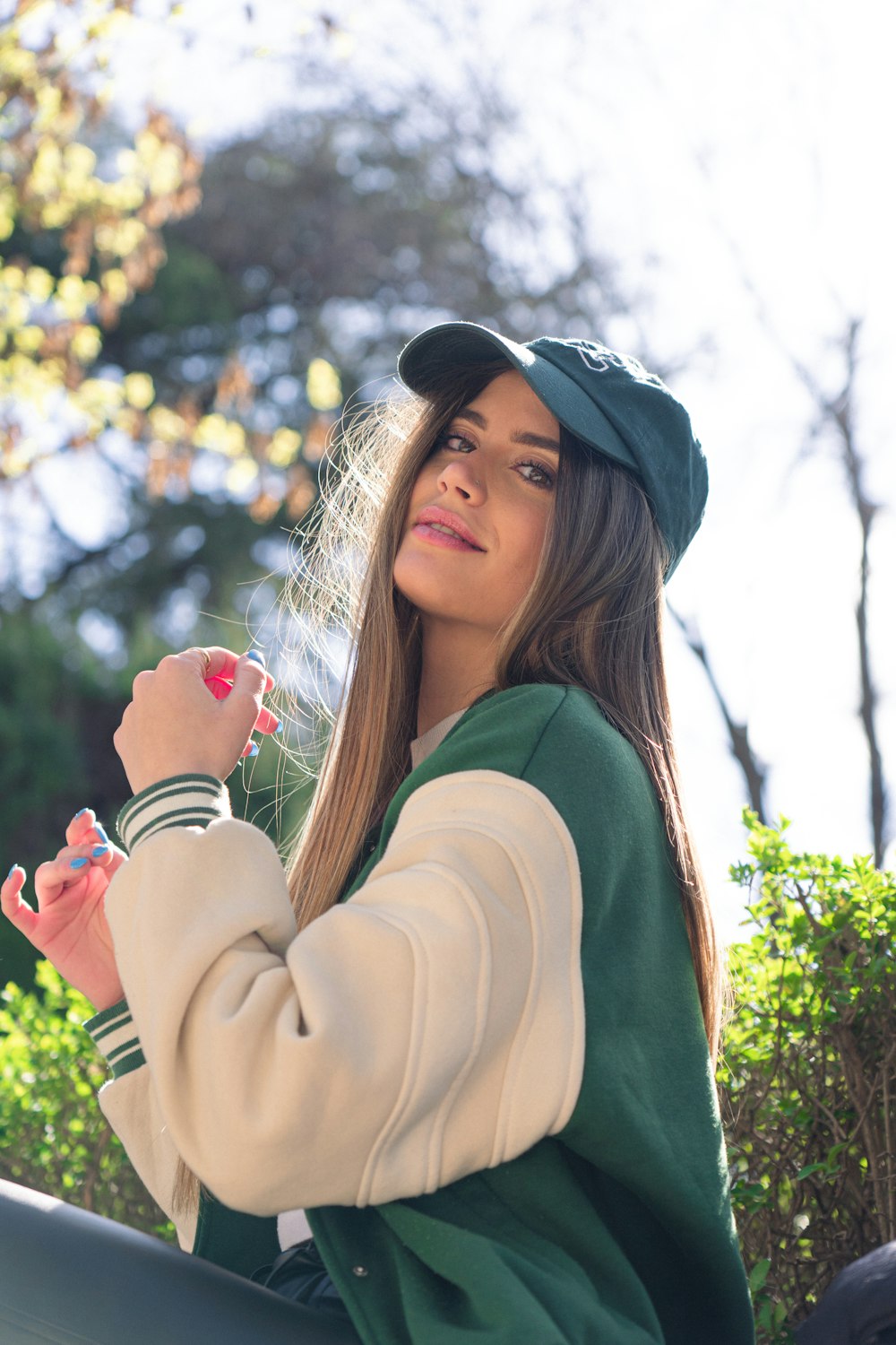 a person with long hair and a green hat holding the hands up