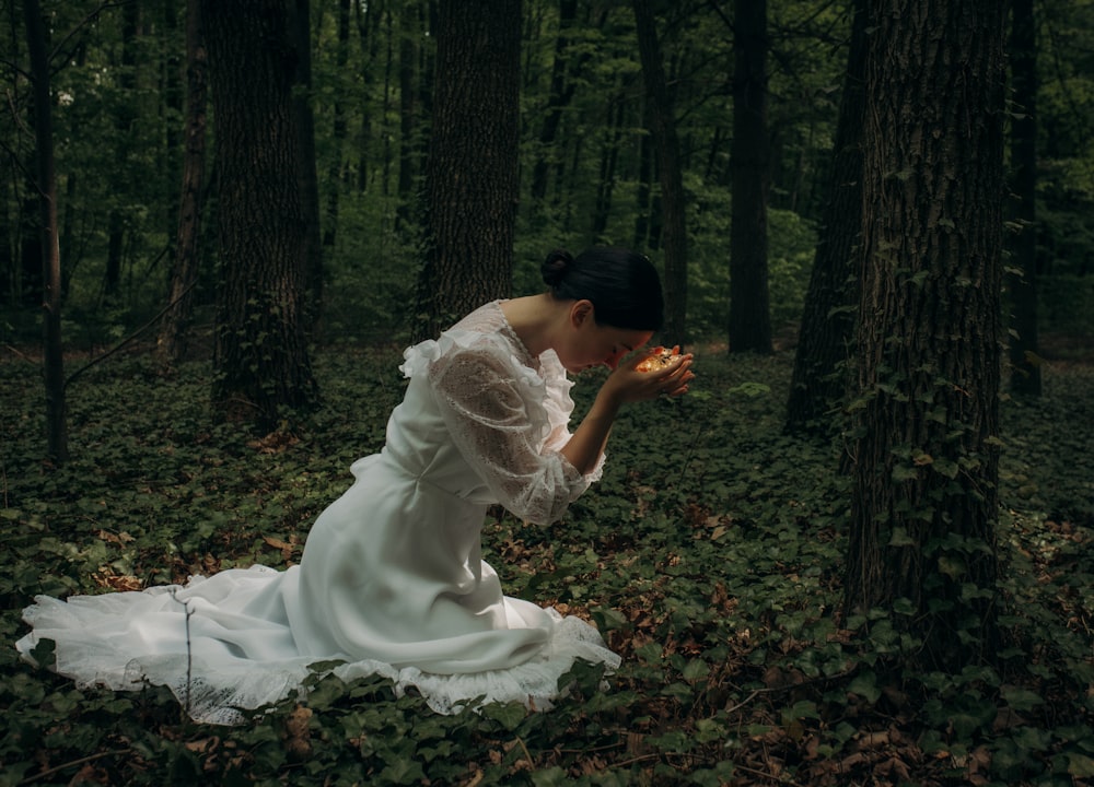 a man in a white dress sitting in a forest