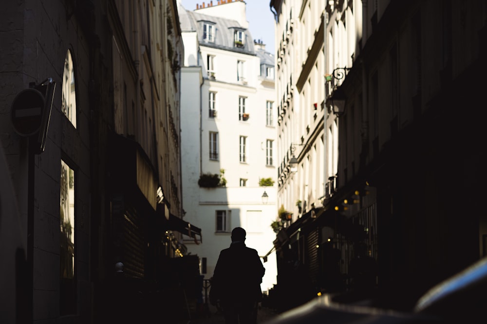 a person walking down a street between buildings