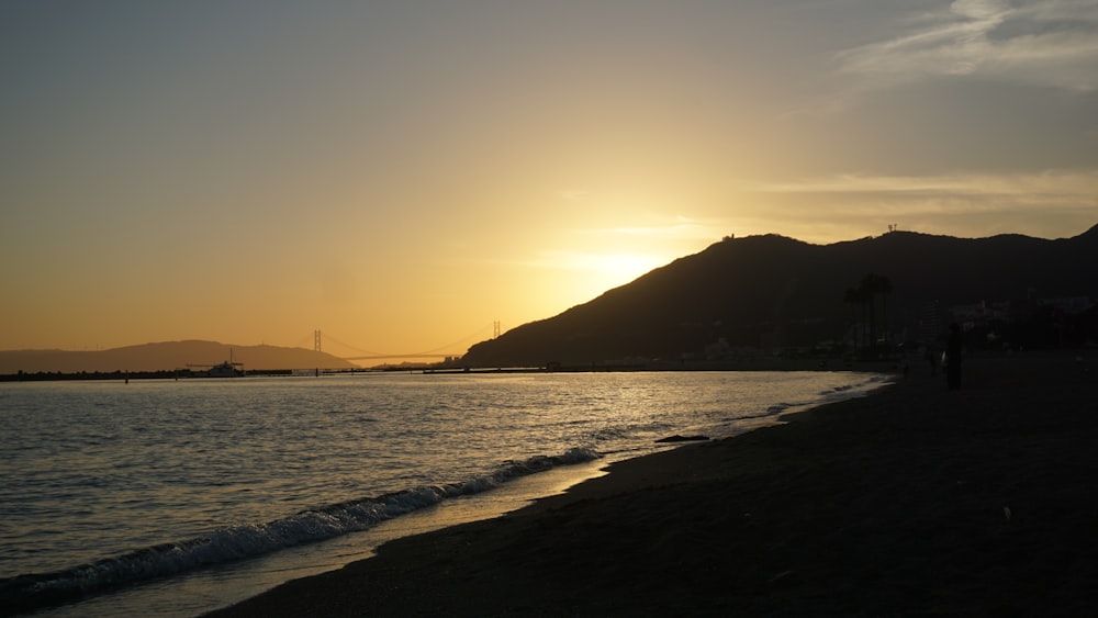 a beach with a body of water and a hill in the background