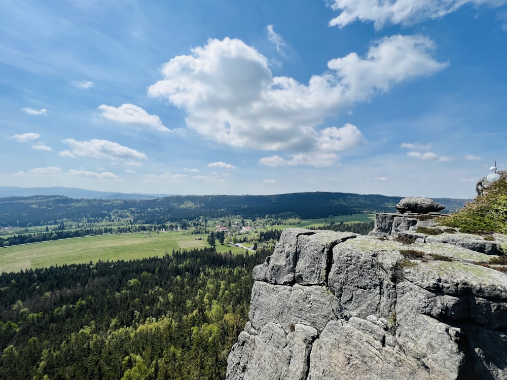 a large rock overlooking a green landscape