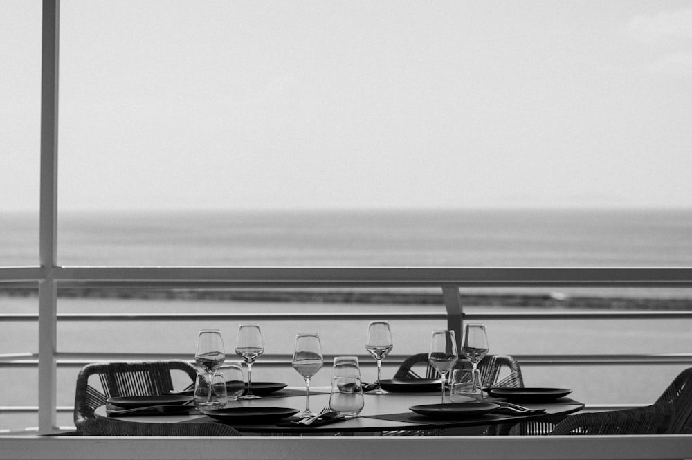 a table with glasses and plates on it by the water