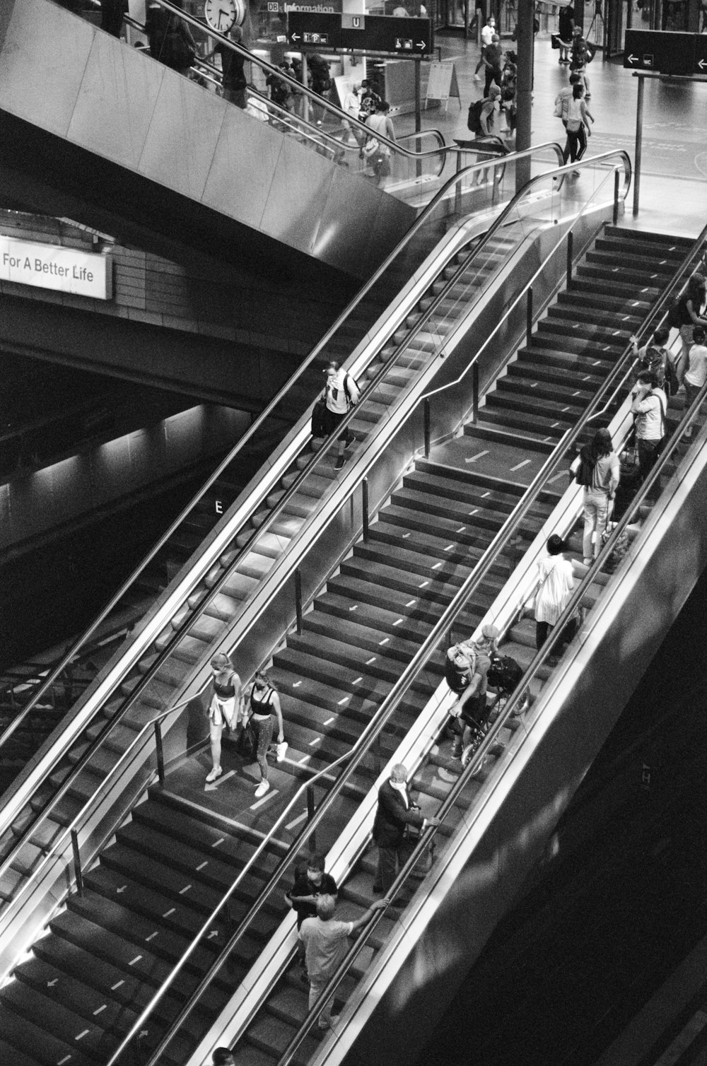 a black and white photo of people on an escalator