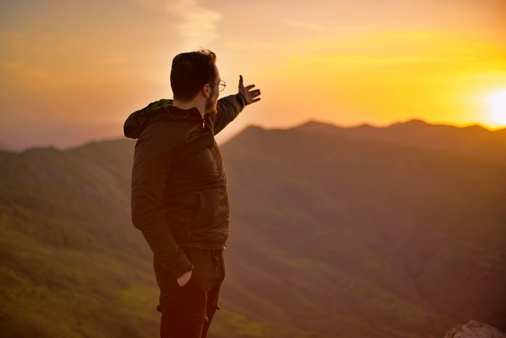 a man standing on top of a lush green hillside