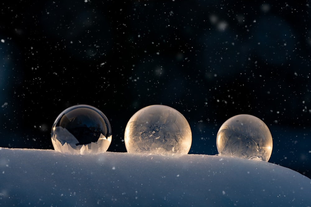 three snow globes sitting on top of a snow covered hill