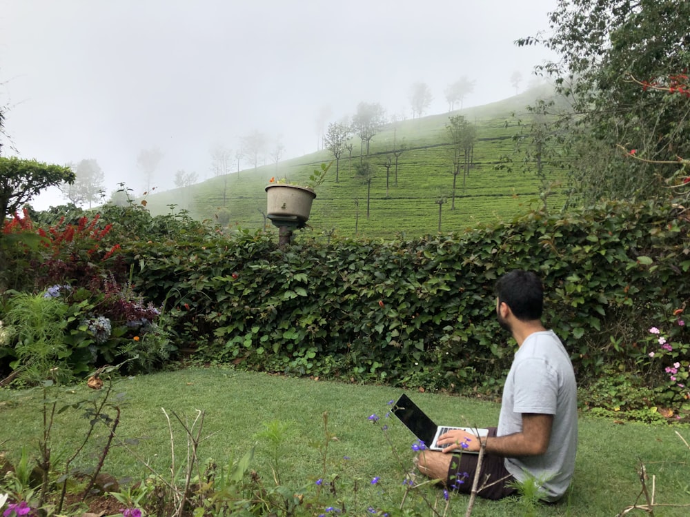 a man sitting on the grass with a laptop