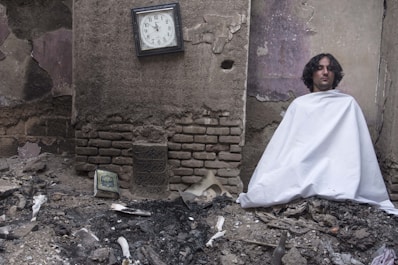 a man wrapped in a white cloth sitting on a pile of rubble