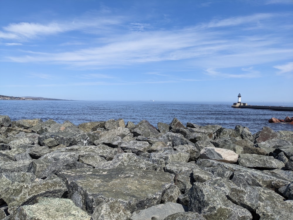 a rocky beach with a lighthouse in the distance