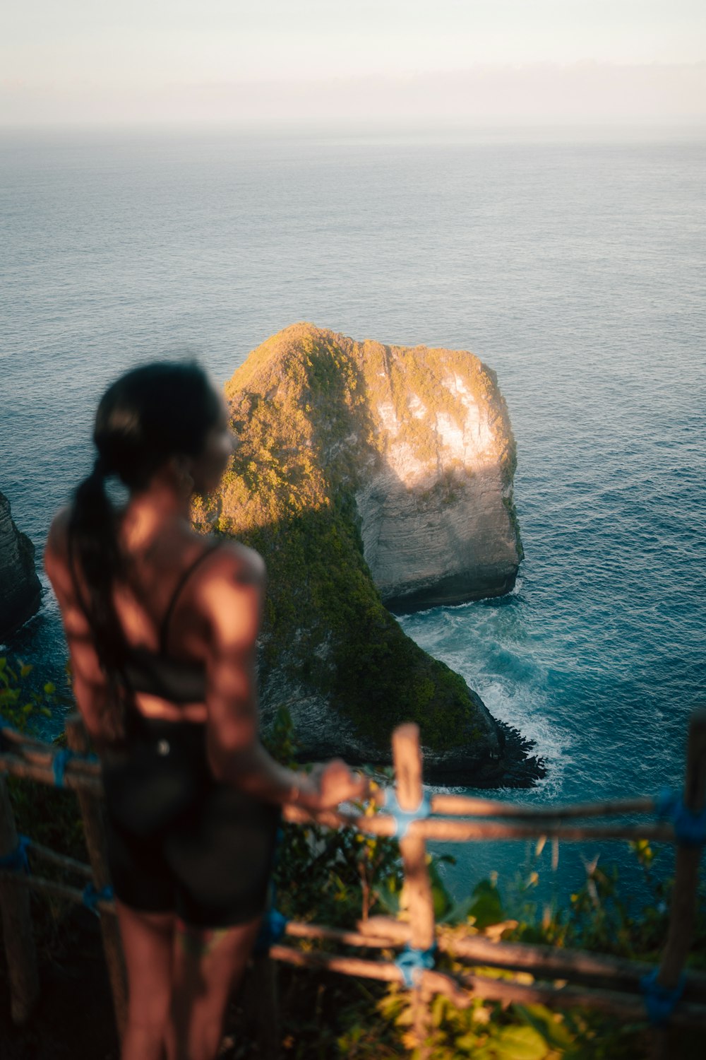 a woman standing on top of a cliff next to the ocean