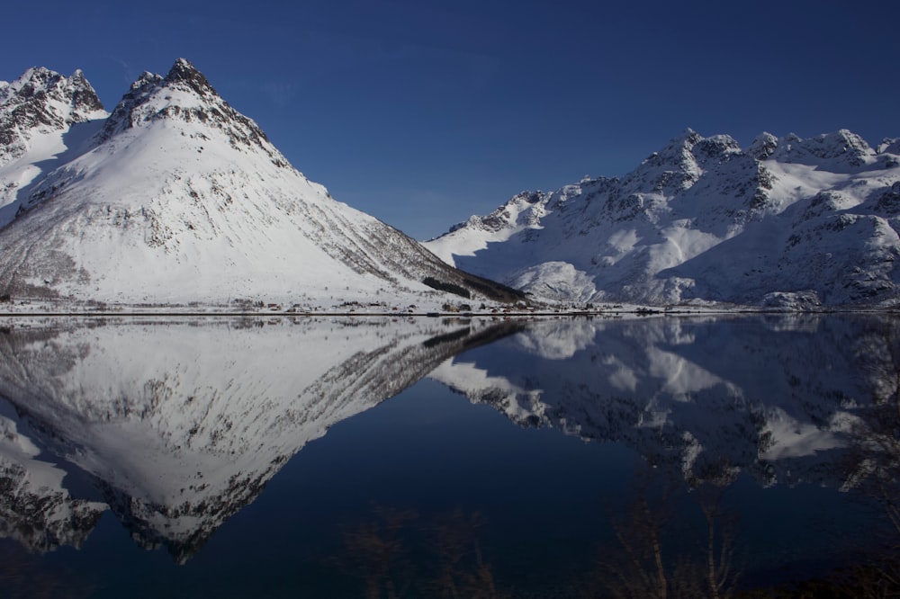 a snow covered mountain sitting next to a lake