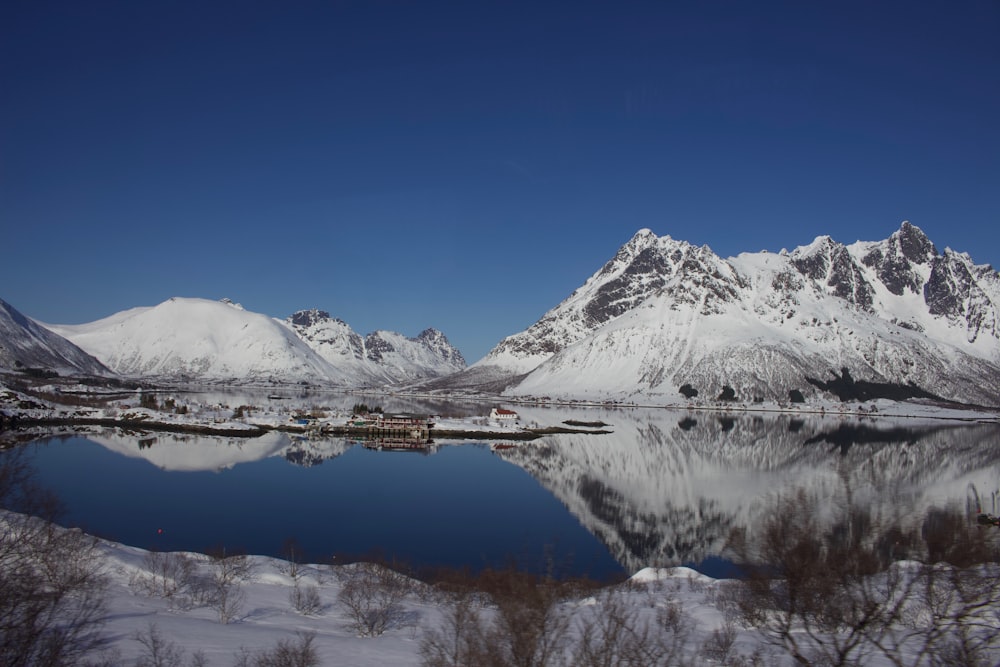 a lake surrounded by snow covered mountains under a blue sky