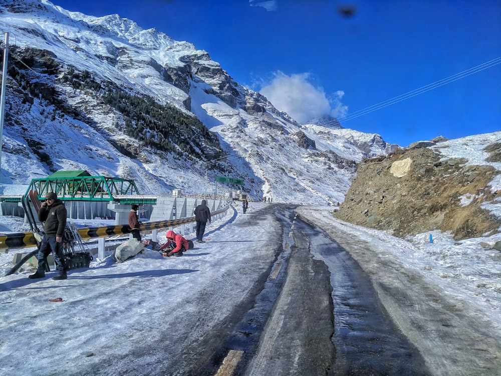 Un gruppo di persone in piedi sul ciglio di una strada innevata