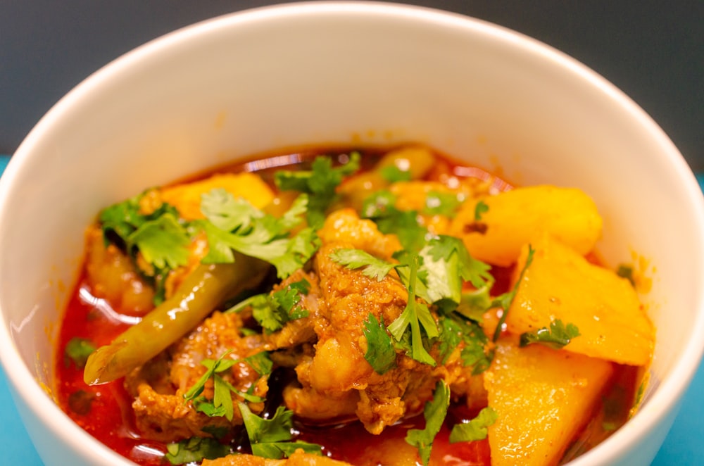 a white bowl filled with meat and vegetables